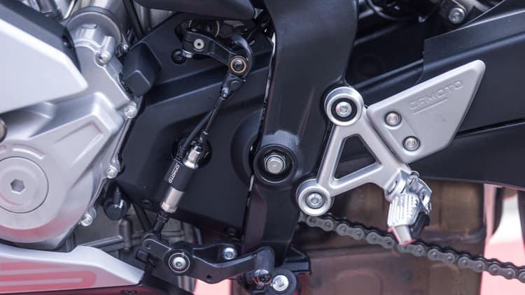 Quick shifter memungkinkan perpindahan gigi naik dengan lebih cepat tanpa perlu menarik tuas kopling. Slipper clutch membantu mengurangi efek engine braking berlebih dan menjaga kestabilan roda belakang saat melakukan downshift.
