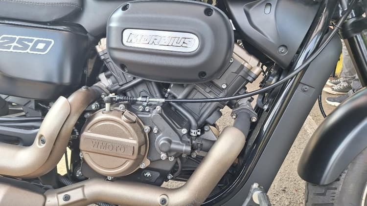 Mesin V-Twin 249 cc dengan konfigurasi 2 silinder, 4 katup DOHC, dan pendingin cairan menghasilkan karakter tenaga yang responsif serta tampilan mesin yang khas motor cruiser.
